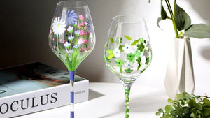 Two hand-painted wine glasses with floral designs on a white surface.